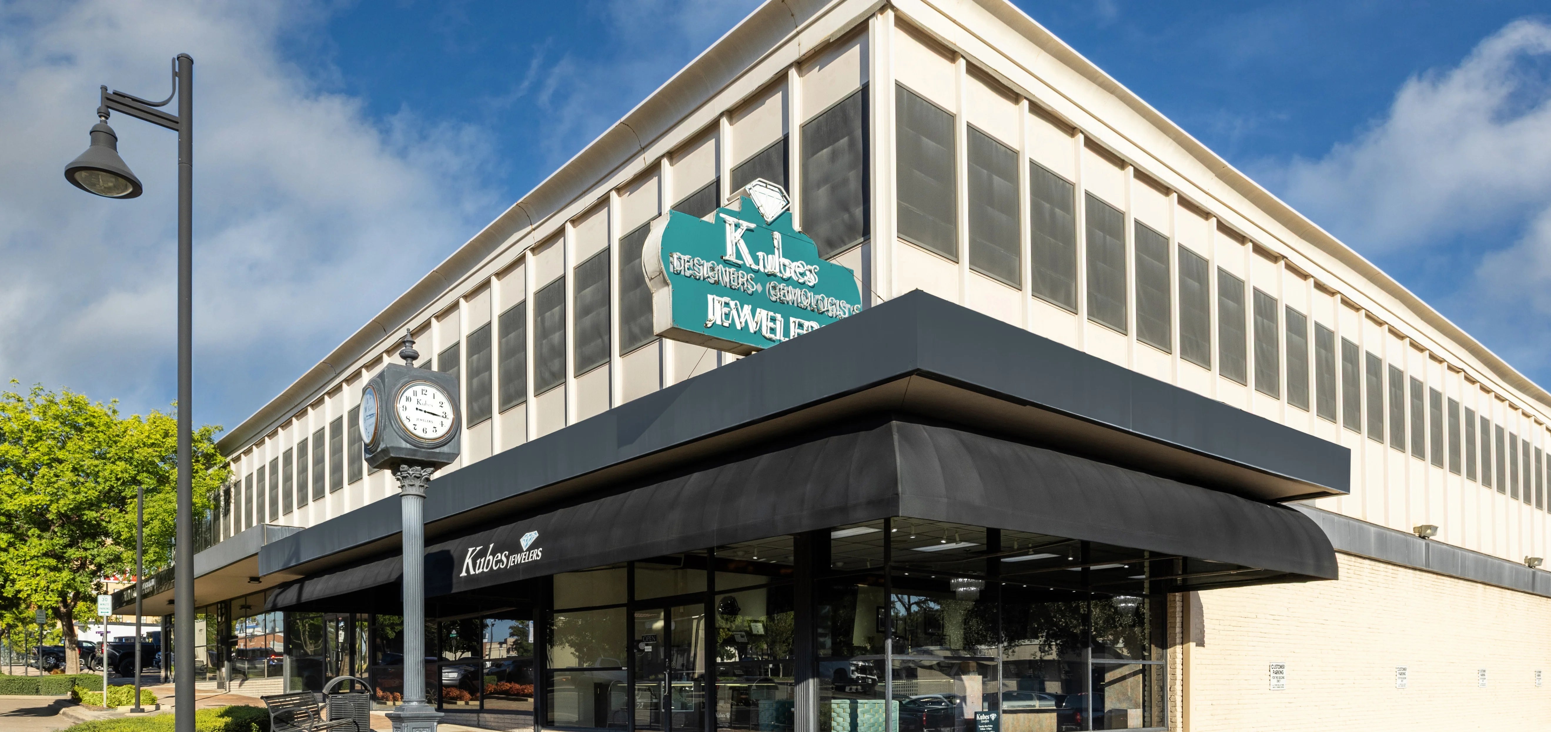 Corner building with a clock and 'Kubes' sign under a blue sky.