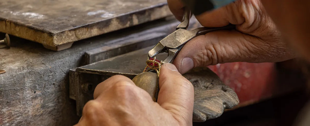 Close-up of hands working with jewelry on a rustic surface